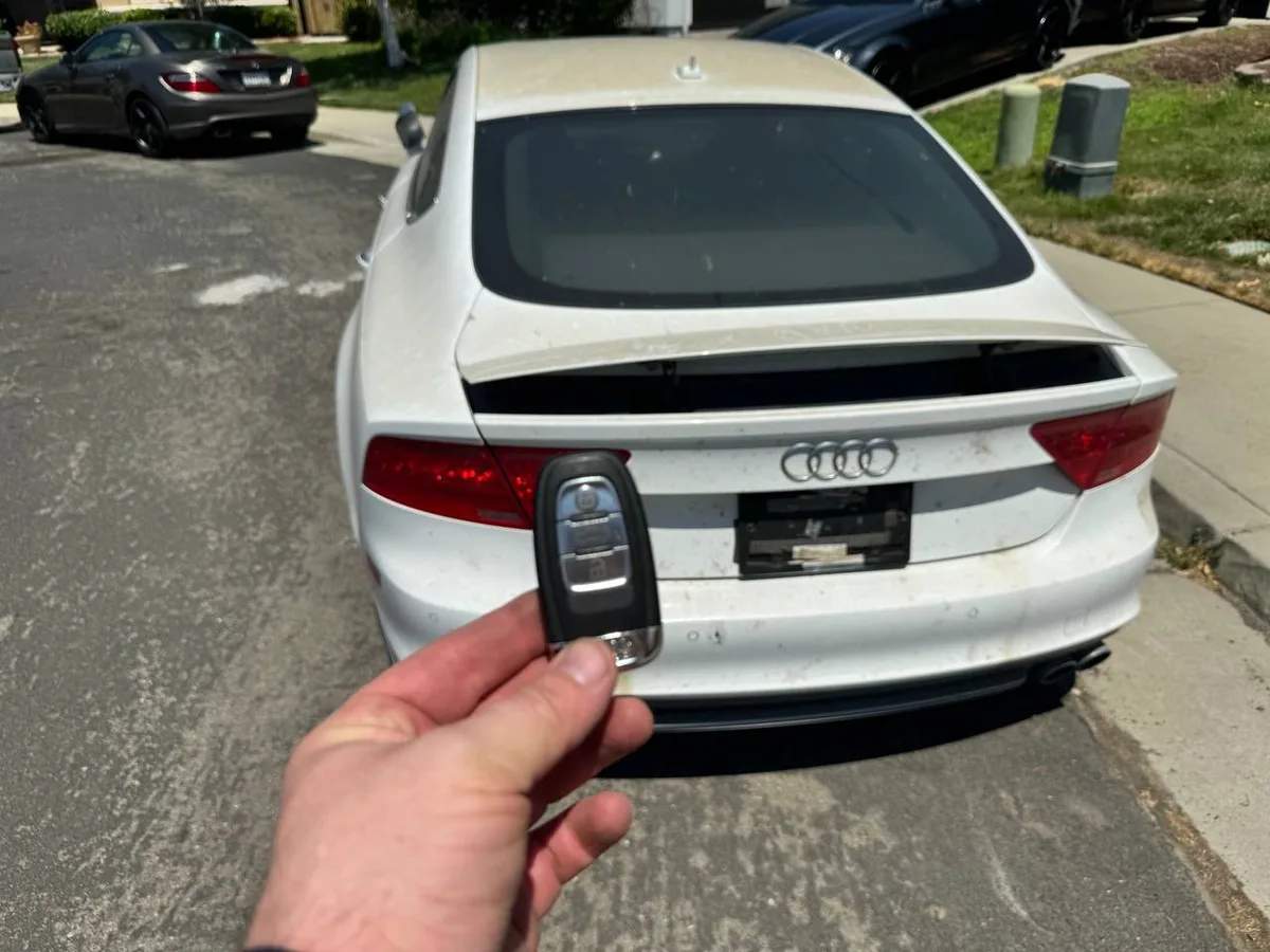 Locksmith holding an Audi key fob in front of an Audi during a key duplication job