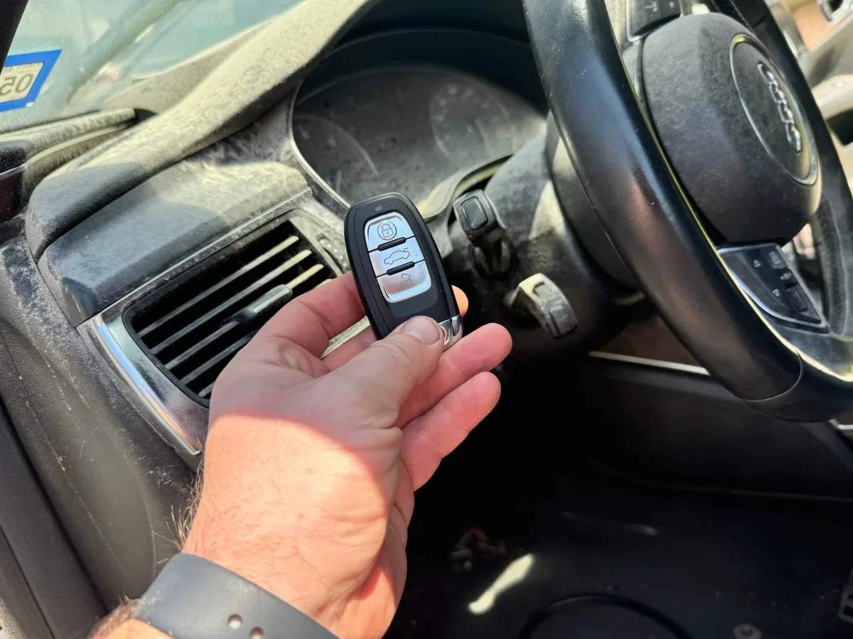 Audi key fob tested near the ignition switch and steering wheel during a programming job