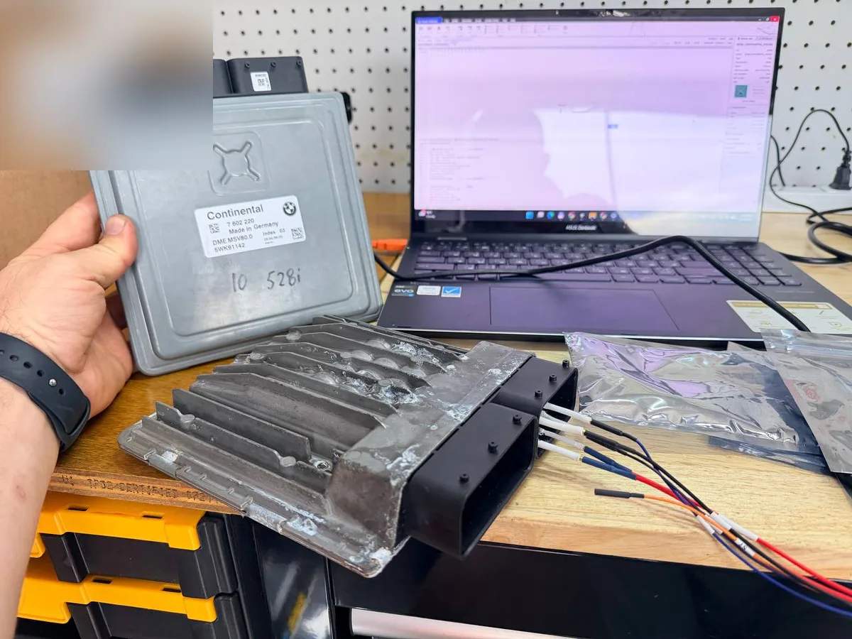 BMW DME engine control module and ignition coil pack on a workbench during ECU programming work