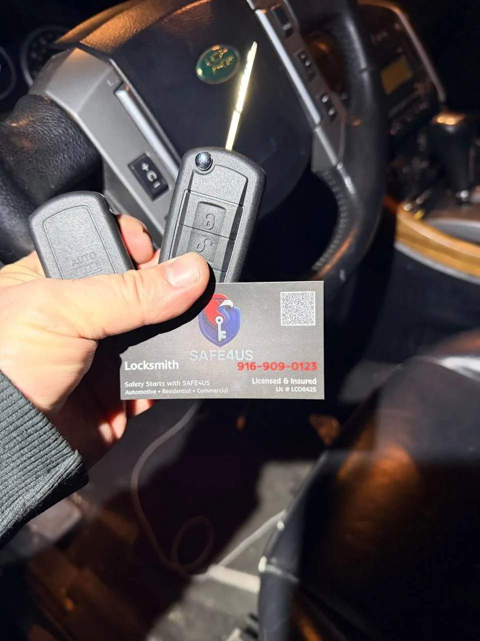 Land Rover key fob held next to a Safe4us business card inside the cabin during key programming