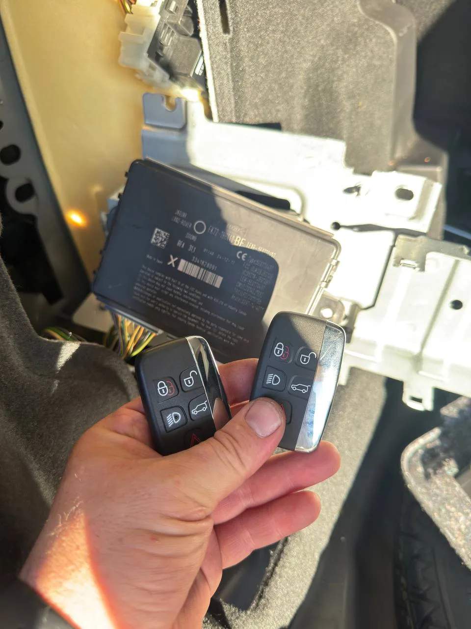 Two Land Rover smart key fobs held beside the vehicle's body control module during programming
