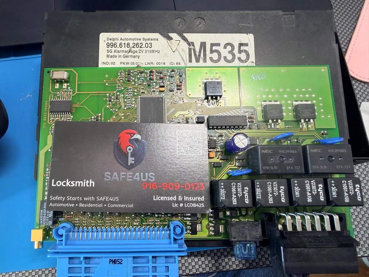 Porsche alarm control module circuit board and Safe4us business card photographed during module work