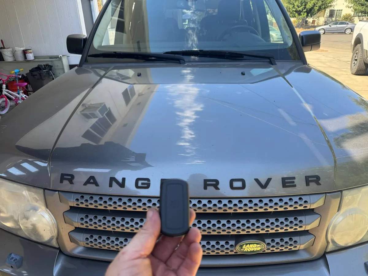 Locksmith holding a Range Rover key fob in front of the vehicle during a key programming job