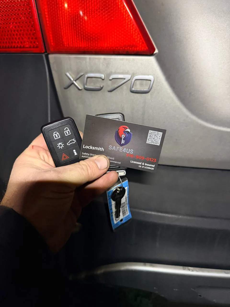 Two duplicated Volvo key fobs shown with a Safe4us business card at the rear of the vehicle